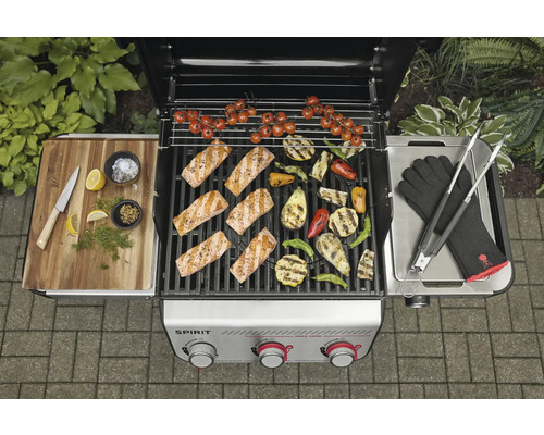 Grillszene mit Lachs, Gemüse und Grillzubehör auf einem Gasgrill