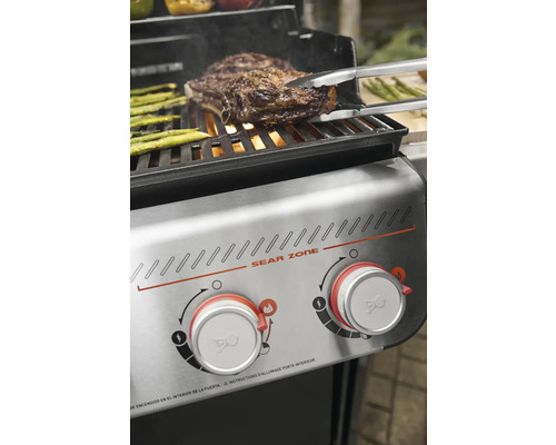 Grill mit Steak und Spargel auf dem Rost und Sear Zone Bedienelementen.