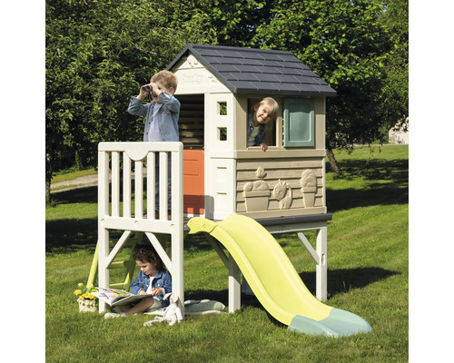 Kinder spielen in einem Smoby Kletterhaus mit Rutsche im Garten.
