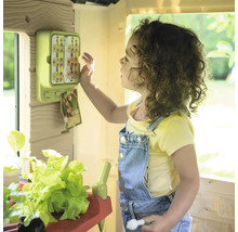 Mädchen spielt mit einem Spielhaus mit Gartenthema und Zubehör