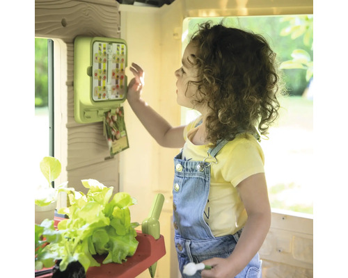 Mädchen spielt mit einem Spielhaus mit Gartenthema und Zubehör