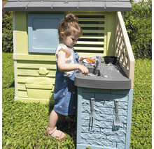 Mädchen spielt in einem Spielhaus mit Spielküche im Garten