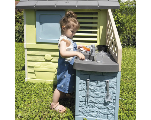 Mädchen spielt in einem Spielhaus mit Spielküche im Garten