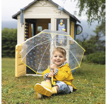 Kind mit gelbem Regenmantel, Regenstiefeln und Regenschirm vor einem Spielhaus