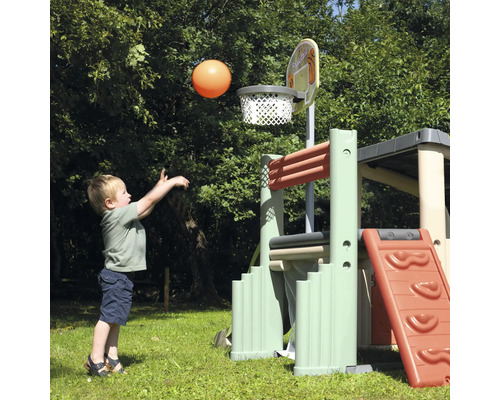 Junge wirft einen Ball in einen Basketballkorb an einem Spielturm im Garten