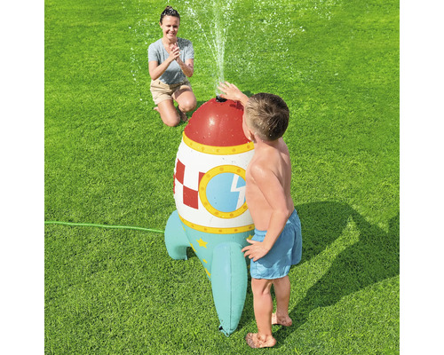 Wasserspielzeug Rakete mit spielendem Kind und zuschauender Frau im Garten