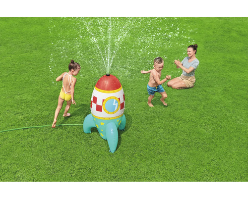 Aufblasbare Raketensprengeranlage für Kinder auf Rasen mit spielenden Kindern und einer Frau