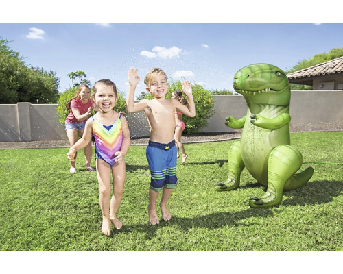 Kinder spielen mit einem aufblasbaren Dinosaurier-Gartensprenger auf einer Rasenfläche.