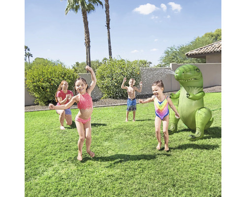 Kinder spielen mit einem aufblasbaren Dinosaurier Wassersprinkler im Garten.