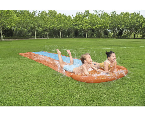 Zwei Kinder haben Spaß auf einer Wasserrutsche im Garten.