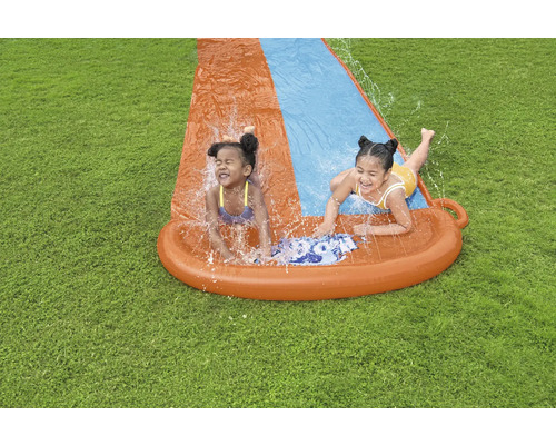 Zwei Kinder haben Spaß auf einer Wasserrutsche im Garten.