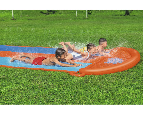 Drei Kinder rutschen auf einer Wasserrutsche im Garten.