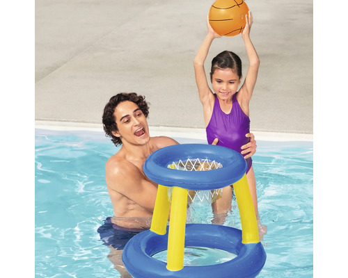 Vater und Tochter spielen mit einem aufblasbaren Basketballkorb im Schwimmbad.
