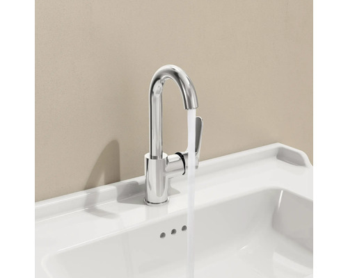 Verchromter Wasserhahn auf weißem Waschbecken mit laufendem Wasser