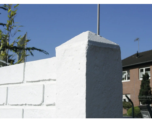 Detailaufnahme einer weißen Mauerabdeckung auf einer Ziegelmauer