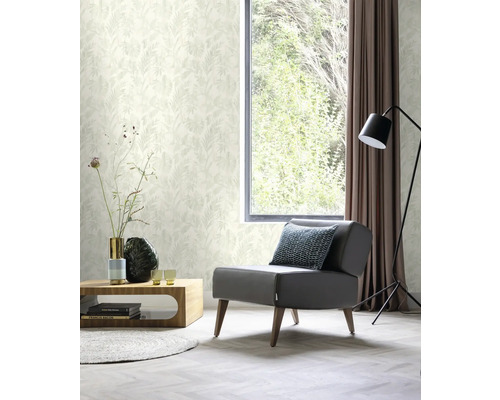 Heller Wohnraum mit Sessel, Tisch, Stehlampe, Vorhang und floral gemusterter Tapete