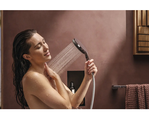 Frau unter der Handbrause im Badezimmer