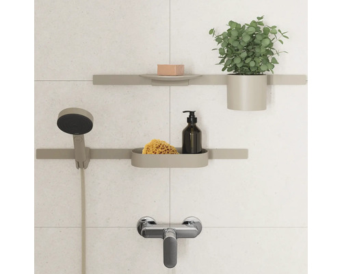 Badezimmeransicht mit Duschkopf, Armatur und Ablagesystem mit Seife, Schwamm, Seifenspender und Pflanze