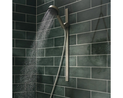 Handbrause mit Brauseschlauch an grüner Fliesenwand mit Wasserstrahl