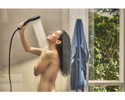 Frau benutzt Handbrause im Badezimmer.