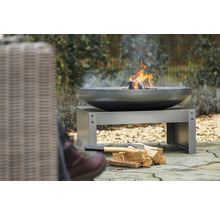 Feuerschale mit Holz auf einem Metallsockel im Garten.
