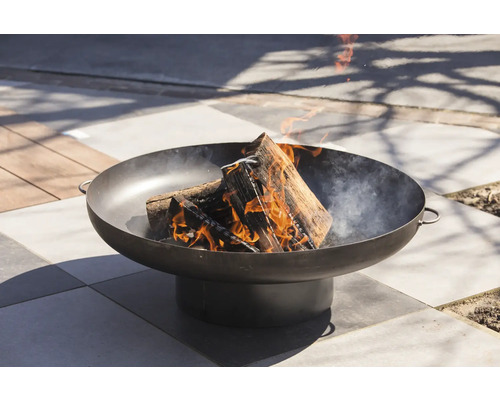 Feuer brennt in einer runden Feuerschale aus Metall im Außenbereich.