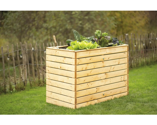 Hochbeet aus Holz mit Salat und Gartenwerkzeug im Garten