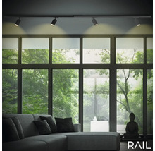 Wohnzimmer mit Schienensystemleuchten, Sofa und Fensterfront mit Blick ins Grüne