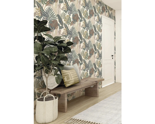 Dekorative Tapete mit Blättermuster hinter Holzhocker mit Kissen und Zimmerpflanze in geflochtenem Korb