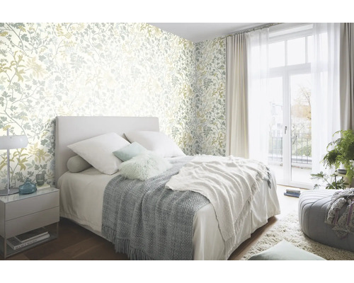 Schlafzimmer mit floral gemusterter Tapete, Bett und Tagesdecke