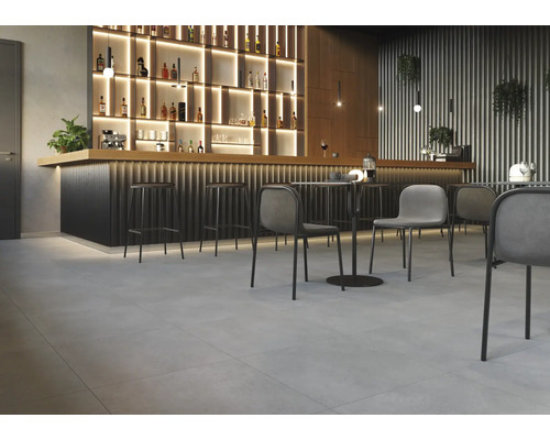 Innenraum mit Bar, Barhockern, Tischen und Stühlen auf Fliesenboden.