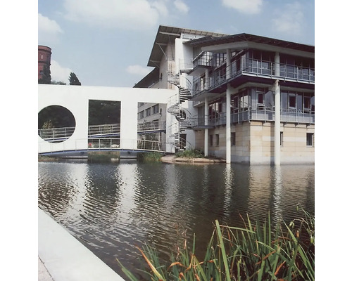 Architekturaufnahme eines modernen Gebäudes mit spiralförmiger Treppe und Brücke über einen Wassergraben