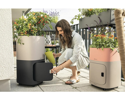 Frau öffnet Pflanzgefäß mit Stauraum auf dem Balkon