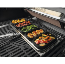Verschiedene gegrillte Speisen in Schalen auf einem Grill