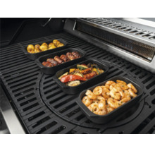 Verschiedene Speisen in Grillpfannen auf einem Grill, darunter Kartoffeln, Fleischröllchen, Gemüse und Garnelen.