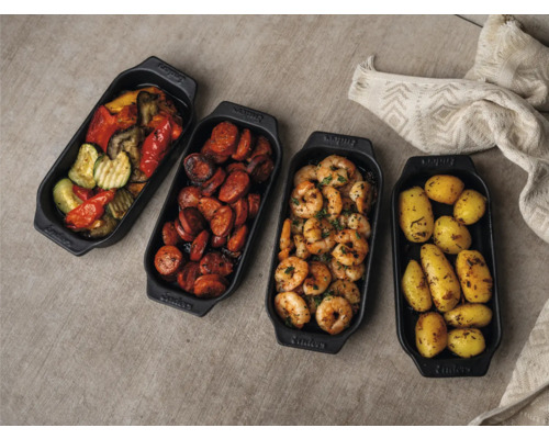 Vier schwarze Servierpfannen mit Gemüse, Wurst, Garnelen und Kartoffeln