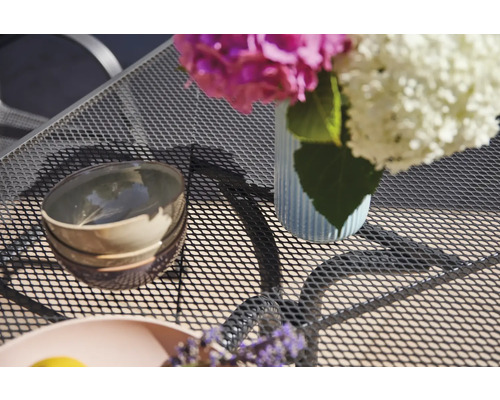 Tischdekoration mit Blumen, Schalen und Geschirr auf einem Gartentisch