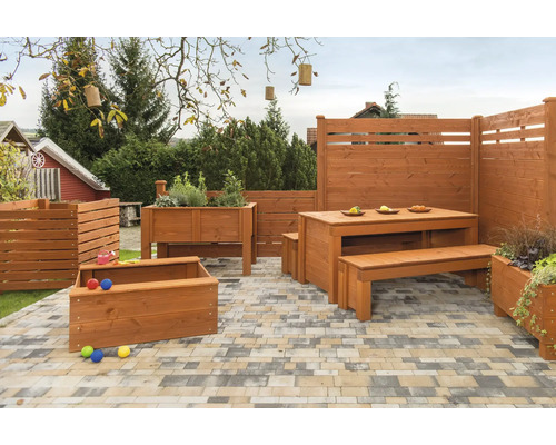Gartenmöbel aus Holz, Hochbeet und Sichtschutzzaun auf einer Terrasse.