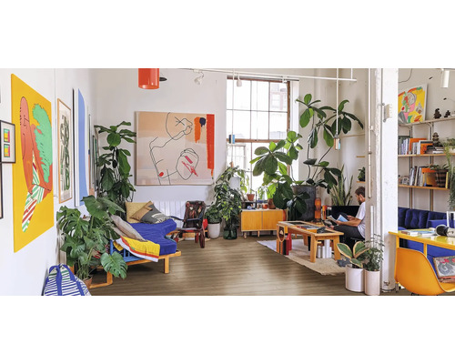 Wohnzimmer mit Möbeln, Pflanzen und Kunstwerken auf Holzboden