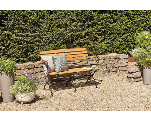 Gartenbank aus Holz mit Kissen und Buch in Gartenszene