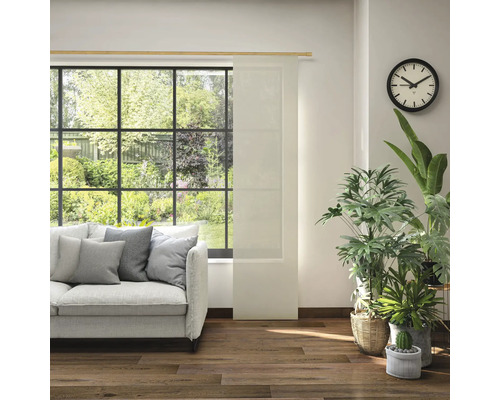 Wohnzimmer mit Sofa, Zimmerpflanzen, Uhr und Schiebegardine vor dem Fenster