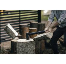 Mann spaltet Holz mit einer Axt auf einem Holzscheit