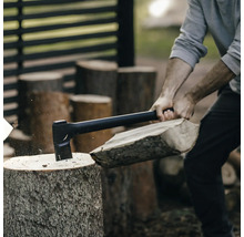 Eine Person spaltet mit einer Axt Holz.