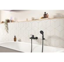Badezimmer mit Badewanne, schwarzer Armatur und geometrischen Fliesen