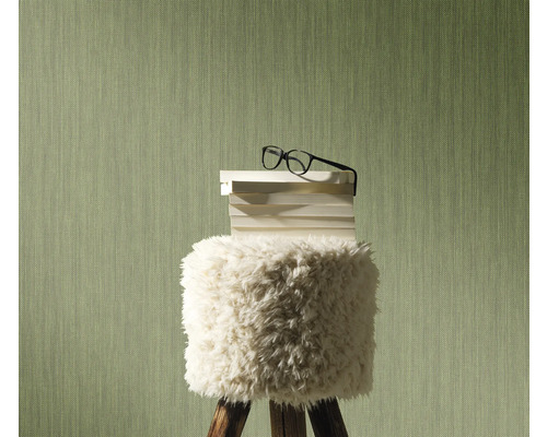 Dekorative Szene mit einem Hocker, auf dem Bücher und eine Brille liegen, vor einer strukturierten Wand