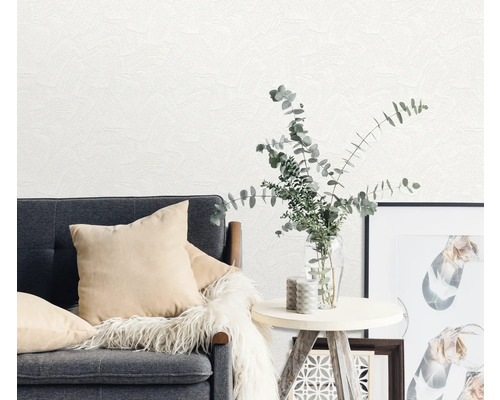 Wohnzimmerszene mit grauer Couch, Kissen, Tisch, Vase mit Pflanzen und Wandtapete