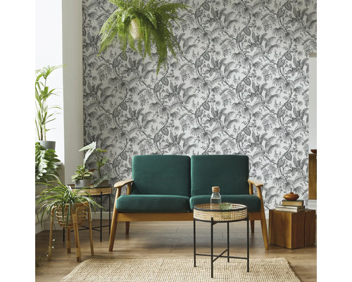 Wohnzimmer mit Sofa, Beistelltischen, Zimmerpflanzen, Teppich und gemusterter Tapete