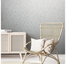 Dekoratives Wohnambiente mit floral gemusterter Tapete, Rattan Sessel und Holzkommode