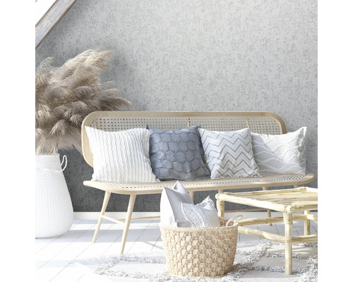 Dekorative Szene mit Rattanbank, Kissen, Rattantisch und Blumenvase vor einer floralen Tapete