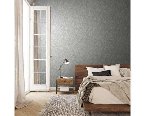 Schlafzimmer mit gemusterter Tapete, Holzbett und Nachttischlampe